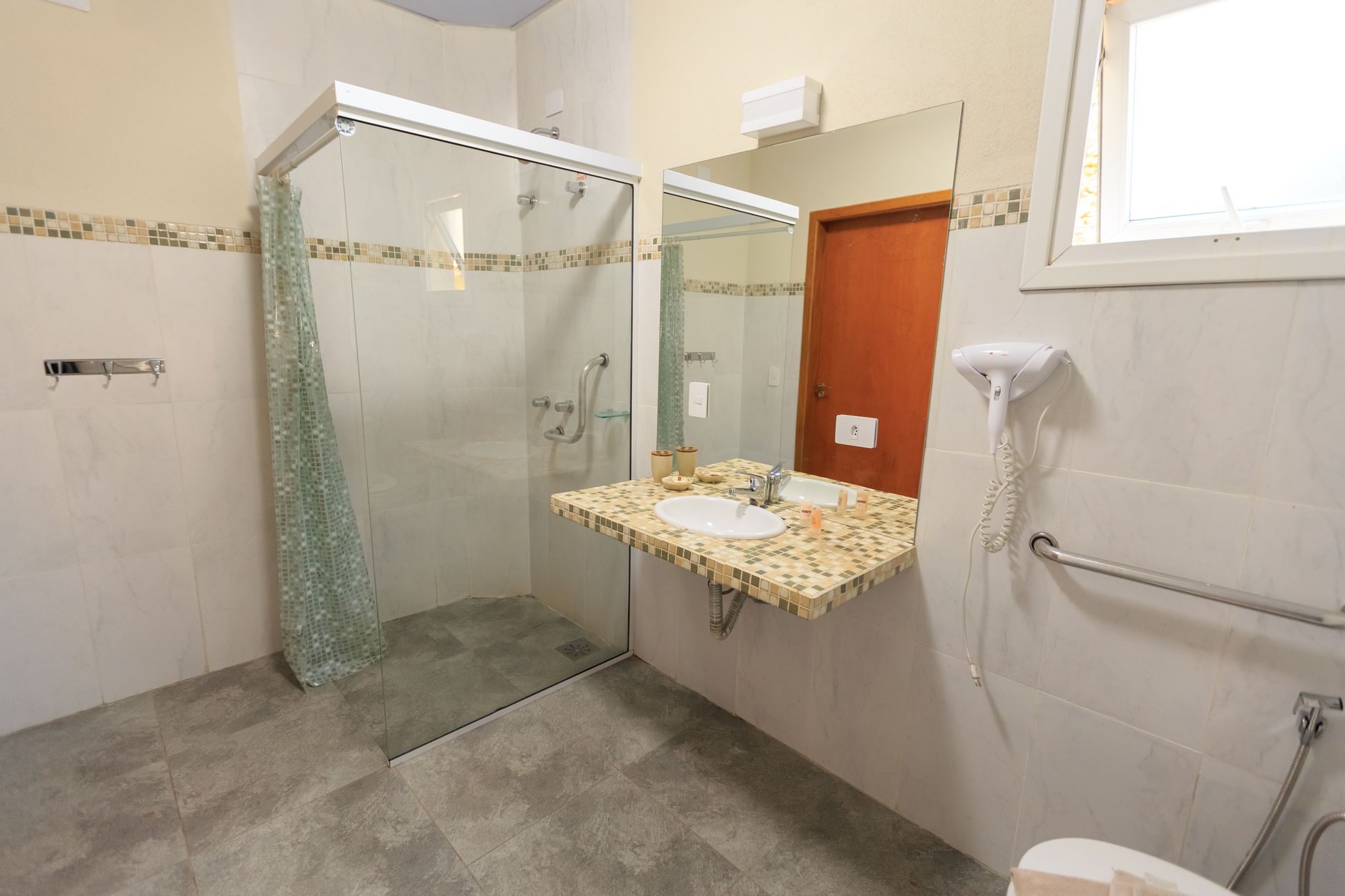 Spacious and accessible bathroom featuring a large glass shower, modern sink, and stylish decor.