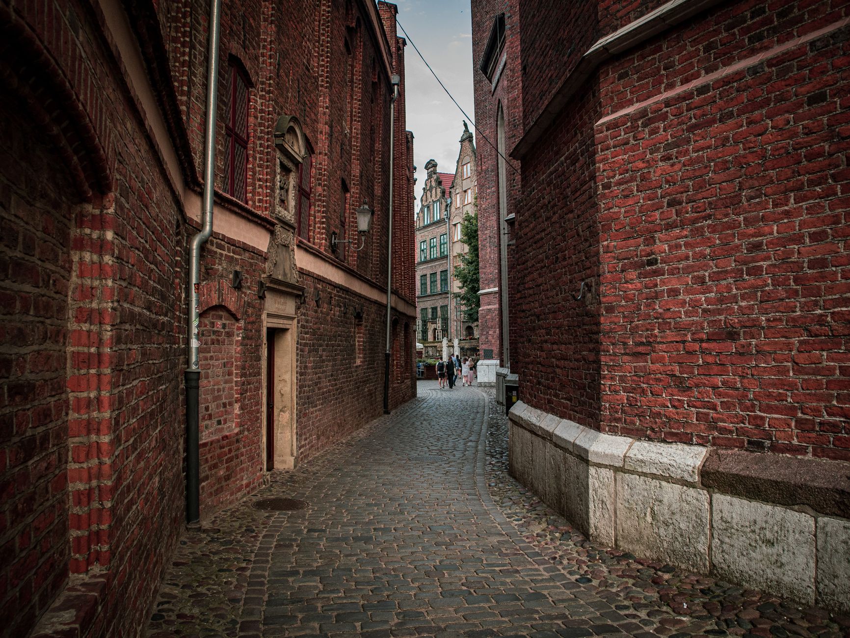 Explore a quaint cobblestone alleyway surrounded by historic brick buildings on a quiet day.