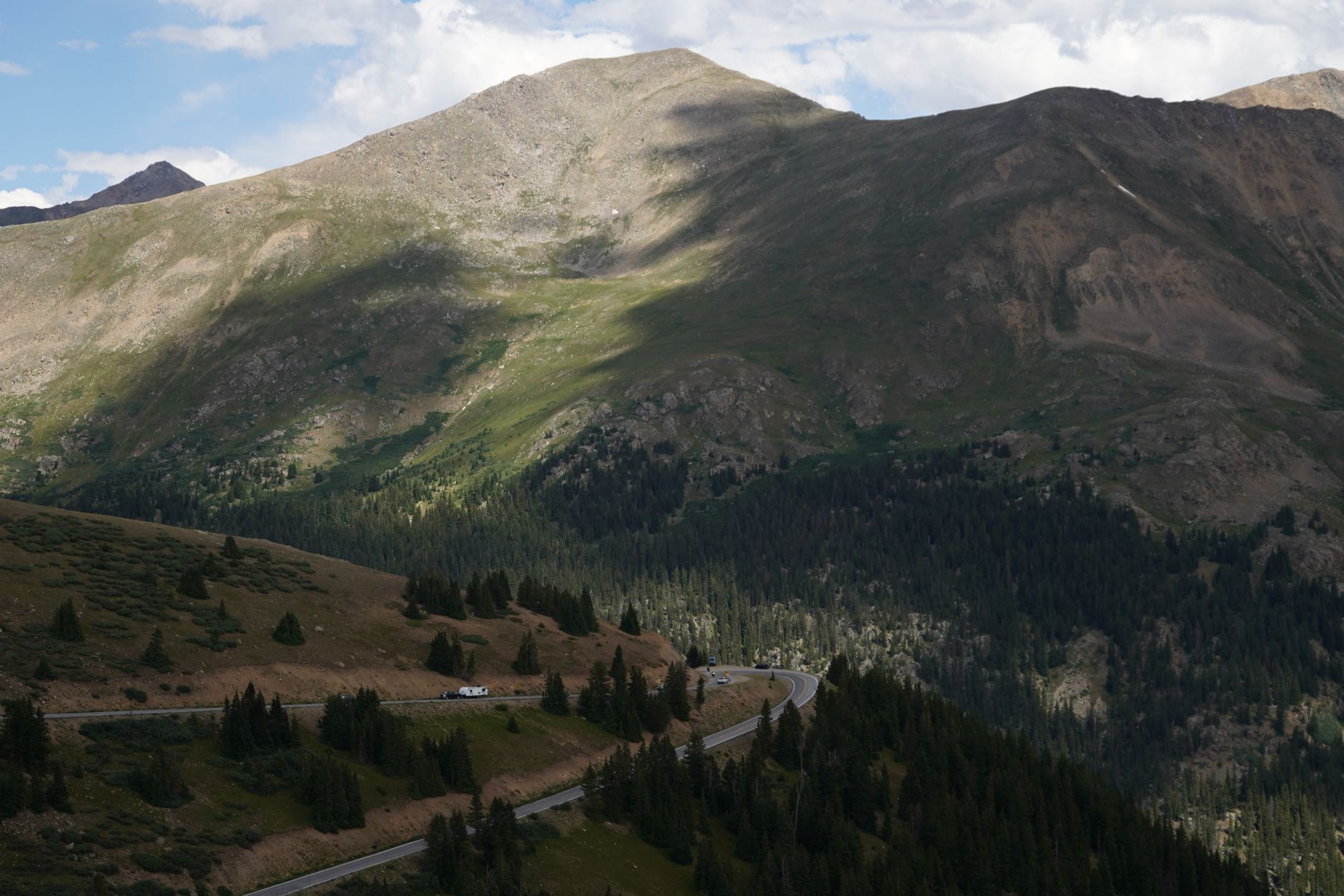 Breathtaking view of a mountain pass with winding road through lush forest, perfect for travel inspiration.