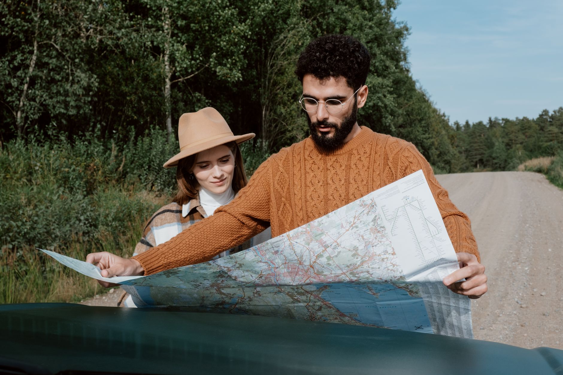 A young couple examines a map on a scenic outdoor road trip.