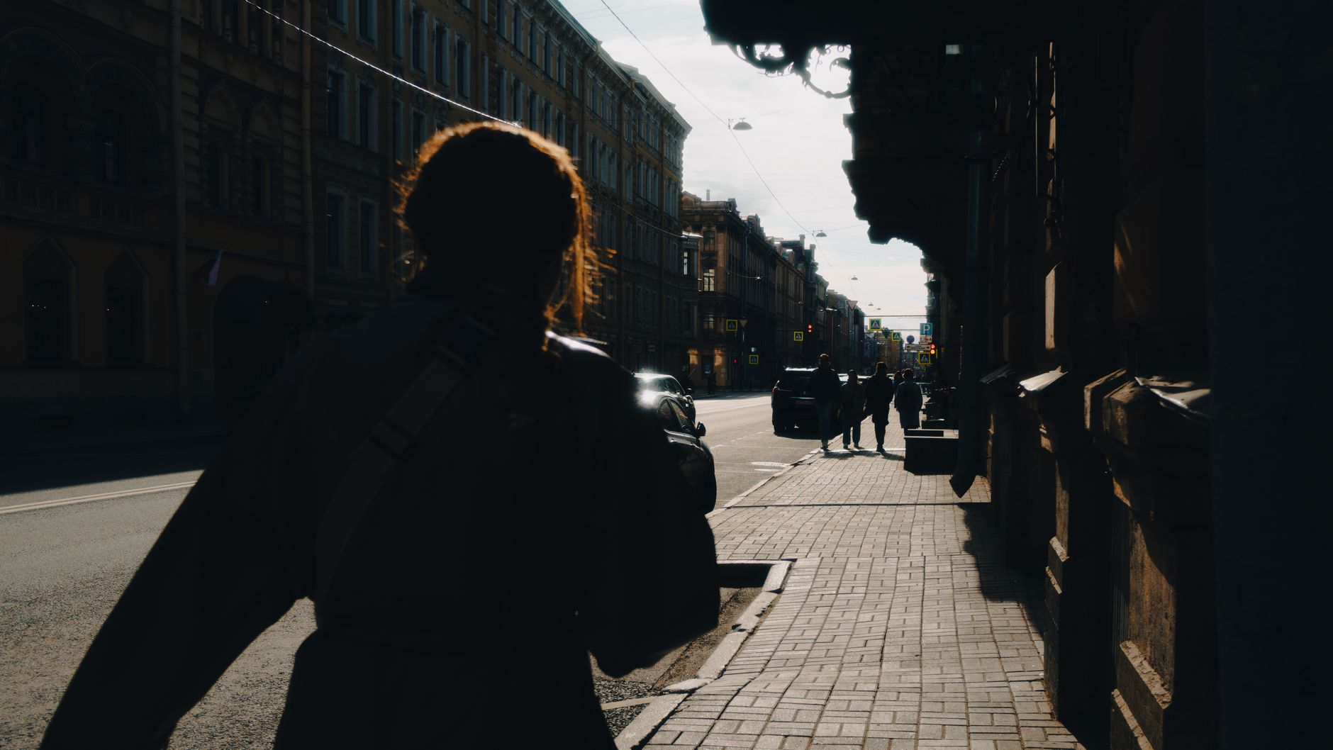 Silhouette of a person walking down a sunlit street in Saint Petersburg, Russia.